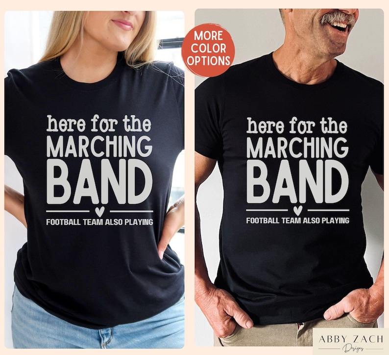 May include: Two black t-shirts with white text that reads "here for the marching band" and "football team also playing".