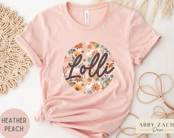 May include: A pink t-shirt with a floral circle design and the name "Lolli" in brown text.