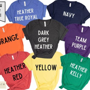 May include: Ten different coloured t-shirts with various text printed on them. The text includes "Match Your Team!" "Heather True Royal", "Orange", "Dark Grey Heather", "Yellow", "Navy", "Team Purple", "Heather Red", and "Heather Kelly".