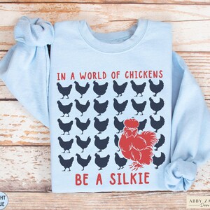 May include: Light blue sweatshirt with a graphic of chickens and the text "In a world of chickens be a silkie".