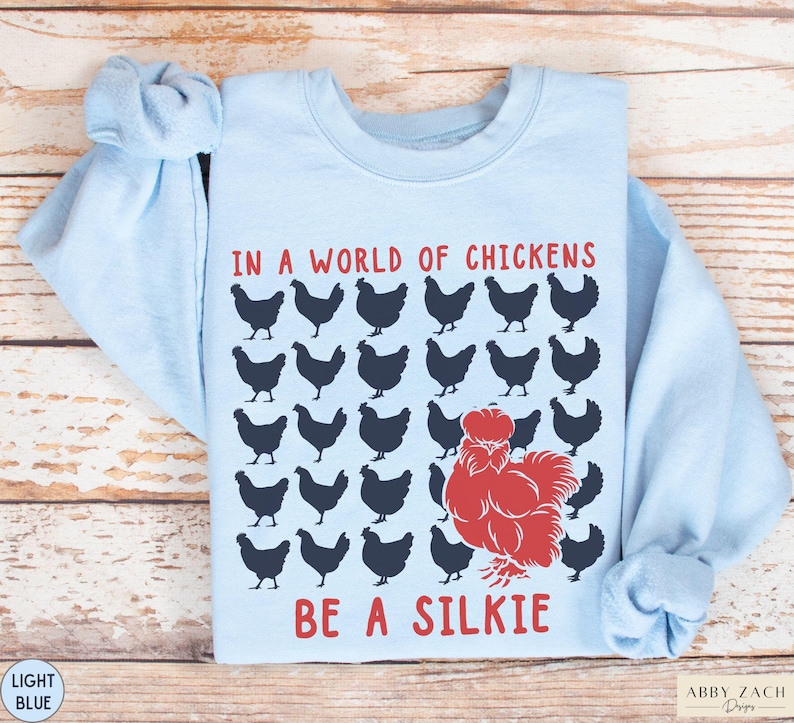 May include: Light blue sweatshirt with a graphic of chickens and the text "In a world of chickens be a silkie".