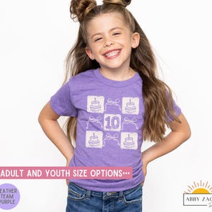 Peut inclure: Un t-shirt en jersey violet avec un motif blanc repr&eacute;sentant un g&acirc;teau avec des bougies et le chiffre 10. Le texte "Adult and Youth Size Options" est en bas de l'image.