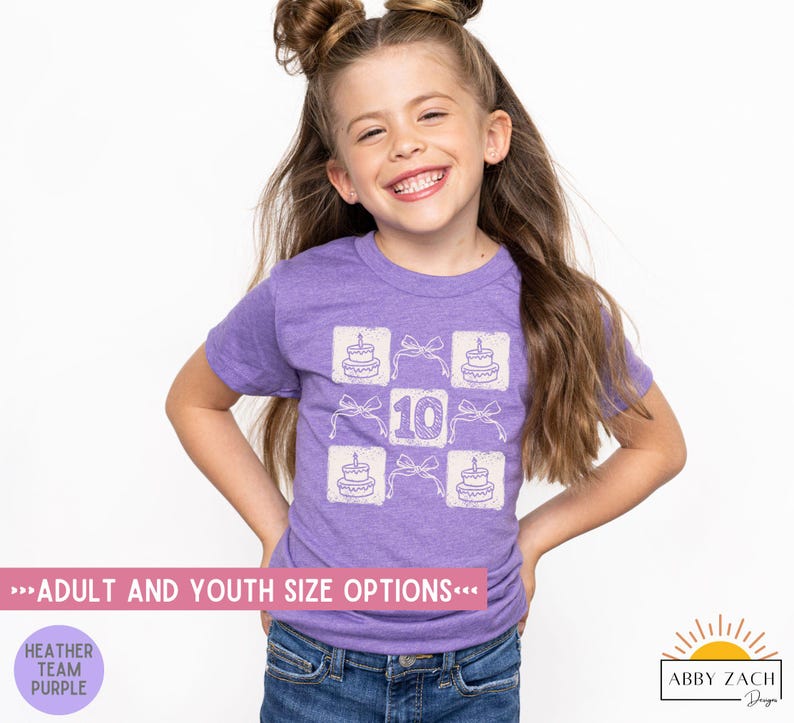 Peut inclure: Un t-shirt en jersey violet avec un motif blanc repr&eacute;sentant un g&acirc;teau avec des bougies et le chiffre 10. Le texte "Adult and Youth Size Options" est en bas de l'image.