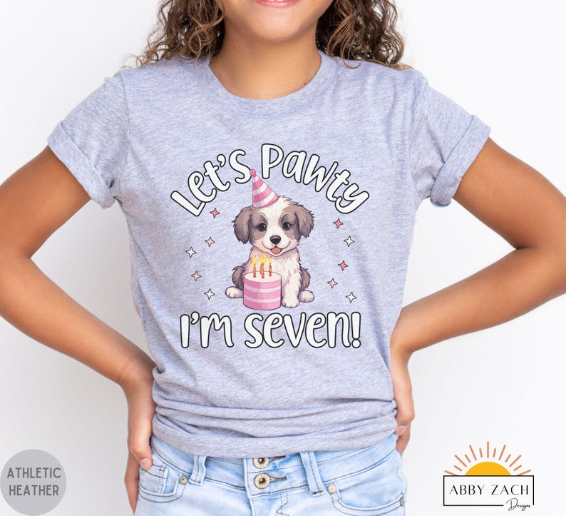 May include: Gray t-shirt with a cartoon dog wearing a party hat and holding a birthday cake. The text on the shirt reads "Let's Pawty I'm Seven!"