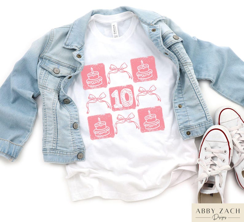 Peut inclure: T-shirt blanc avec un motif rose de cupcakes et le chiffre 10. Le motif est dispos&eacute; en grille.