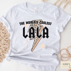 May include: A gray t-shirt with the text "The World's Coolest Lala" in black letters with a leopard print lightning bolt graphic.