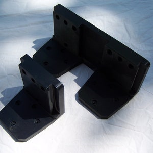 May include: Two black plastic brackets with multiple holes. The brackets are L-shaped and have a flat surface on one side.