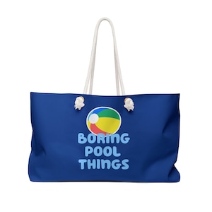May include: A blue tote bag with white rope handles. The bag has a colorful beach ball graphic and the text "BORING POOL THINGS" in blue.