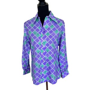 May include: A long-sleeved button-down shirt with a geometric pattern in purple, green, and white. The shirt features a pointed collar and buttoned cuffs. The pattern consists of a grid of diamonds with alternating green and white squares.