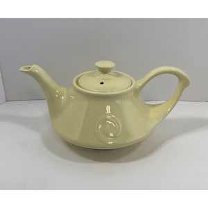 May include: A pale yellow ceramic teapot with a swirl design and a lid. The teapot has a rounded body and a curved handle.