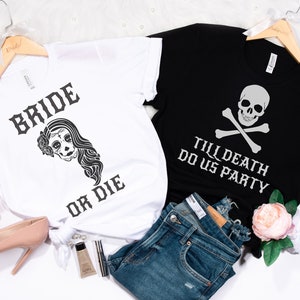 May include: Two white t-shirts with black text and graphics. The first shirt says "Bride or Die" with a sugar skull graphic. The second shirt says "Till Death Do Us Party" with a skull and crossbones graphic.
