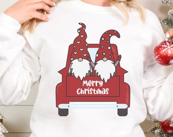 May include: White sweatshirt with a red truck carrying two gnomes. The truck has the words "Merry Christmas" on the back.
