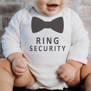 May include: A white baby onesie with a black bow tie graphic and the text "RING SECURITY".