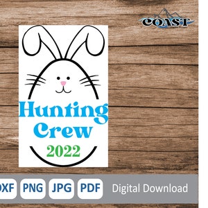 May include: A white Easter egg with a black outline and bunny ears. The egg has a pink nose and black whiskers. The text "Hunting Crew 2022" is written in blue and green letters.