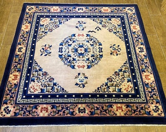 Puede incluir: Una alfombra azul y blanca con un patrón floral. La alfombra tiene un centro de color crema con un gran diseño floral y un borde azul con un patrón repetitivo.