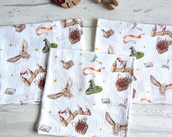 May include: Three white muslin baby burp cloths with a whimsical Harry Potter themed print. The print features owls, a wizard's hat, a castle, and stars.