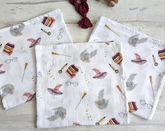 May include: Three white muslin baby burp cloths with a whimsical owl, wizard hat, and book print. The print is in shades of pink, brown, and gold.