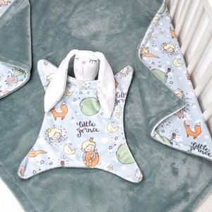 May include: A light blue baby blanket with a white bunny rabbit and a star pattern. The blanket has the words "little prince" printed on it.