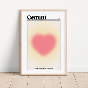 Könnte beinhalten: Gerahmter Kunstdruck mit dem Wort "Gemini" in Schwarz über einem verschwommenen rosa Herz. Der Hintergrund hat einen Farbverlauf aus Gelb- und Pfirsichtönen. Das Wort "AIR" befindet sich oben rechts. Der Druckboden hat die Worte "gentle affectionate adaptable".