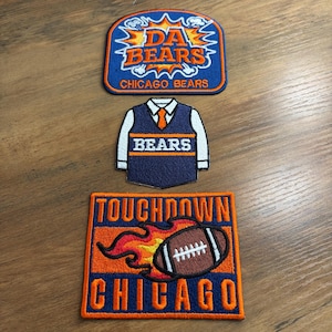 May include: Three embroidered patches with a Chicago Bears theme. The top patch is blue with "DA BEARS" and "CHICAGO BEARS" in white and orange. The middle patch is a navy blue vest with "BEARS" in white. The bottom patch has a football and the words "TOUCHDOWN CHICAGO".