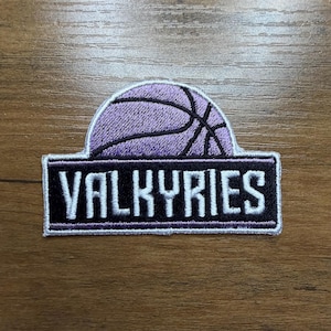 May include: Embroidered patch featuring a purple basketball design above a black rectangle. The word "VALKYRIES" is embroidered in white block letters. The patch has a white border and is likely for apparel or accessories.