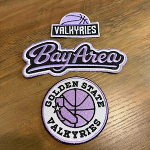 May include: Three embroidered patches in lavender and black. The top patch features a basketball graphic and the text VALKYRIES. The middle patch displays the text Bay Area in script. The bottom circular patch shows a basketball and the text GOLDEN STATE VALKYRIES.