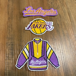 May include: Three embroidered patches featuring purple and yellow colors. The top patch displays the text Los Angeles in script. The middle patch is a circular basketball logo with the text Lakers. The bottom patch is a jacket design.