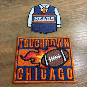 May include: Two embroidered patches. The top patch is a navy blue vest with the word "BEARS" in white. The bottom patch is a football with the words "TOUCHDOWN CHICAGO" and flames in orange and red.