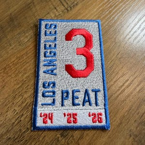 May include: Embroidered patch with a rectangular design. The patch features the words "LOS ANGELES" in blue, a large red number "3", and the word "PEAT" in blue. The bottom has the numbers "'24 '25 '26" in red. The patch has a blue border.