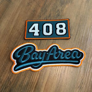 May include: Two embroidered patches. The top rectangular patch features the white number 408 on a teal background with an orange border. The bottom patch features the teal script text Bay Area on a black background with a thick orange border.