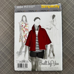 May include: A white ceramic mug with a black handle and the text "But First, Coffee" in a black, handwritten-style font. The mug is on a white surface.