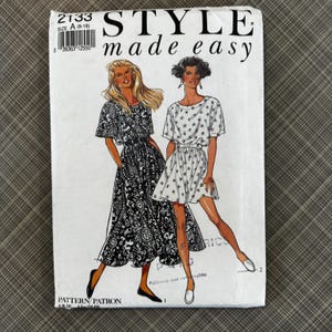 May include: A vintage sewing pattern titled "STYLE made easy" featuring illustrations of two dresses. The pattern is labeled size A (8-18). One dress is black and white paisley, the other is white with a small floral print.