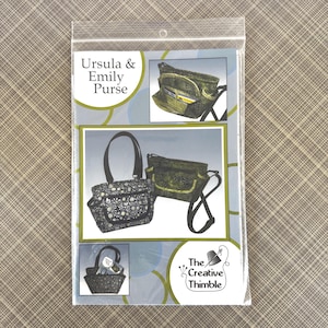 May include: A clear plastic package containing a sewing pattern for an Ursula & Emily Purse. The package features illustrations of the finished purses in various styles, including a tote bag and a crossbody bag. The Creative Thimble logo is visible.