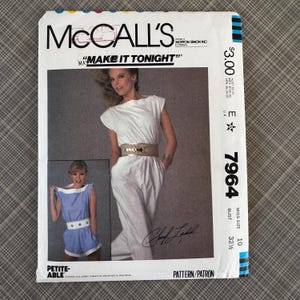 May include: Vintage McCall's sewing pattern envelope for a jumpsuit. The pattern is for size 10, bust 32 1/2 inches. The envelope features a model wearing a white jumpsuit with a belt and a model wearing a blue jumpsuit with a belt. The text on the envelope reads "Make It Tonight" and "Petite-Able".