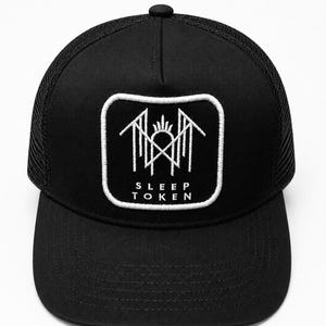 May include: A black trucker hat featuring a square patch on the front panel. The patch has a white border and contains a white embroidered geometric logo above the text SLEEP TOKEN in a clean, sans-serif font. The hat has a solid brim.