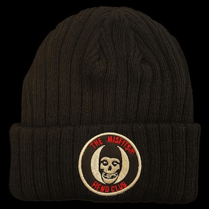 May include: A black ribbed knit beanie featuring a circular embroidered patch on the front cuff. The patch displays a white skull graphic centered within a black circle, surrounded by the red text THE MISFITS and FIEND CLUB in a circular font.