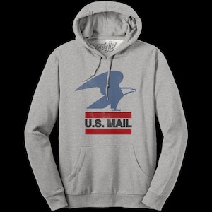 May include: A heather grey hooded sweatshirt featuring a distressed blue eagle graphic above the text U.S. MAIL in black, centered between two horizontal red stripes. The garment includes a front kangaroo pocket and matching grey drawstrings.