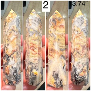 May include: A 3.74 inch tall, multi-colored agate crystal point with a pointed tip and a flat base. The crystal is a mix of white, gray, yellow, and orange colors with a swirling pattern.