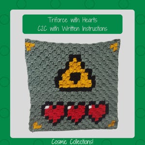 May include: A crocheted pillow featuring a pixelated Triforce symbol in yellow and black, with three red hearts below. The pillow is gray with yellow corner accents. Text on the pillow reads "Triforce with Hearts C2C with Written Instructions" and "Cosmic Collections!"