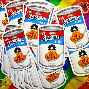 May include: A collection of die-cut stickers shaped like a soup can with a red and blue label. The text reads 'ITS SPAGHETTI TIME' and 'LIQUID STRANGER'. A spoon holds orange pasta shaped like the letters WAKAAN 25N in a red sauce.