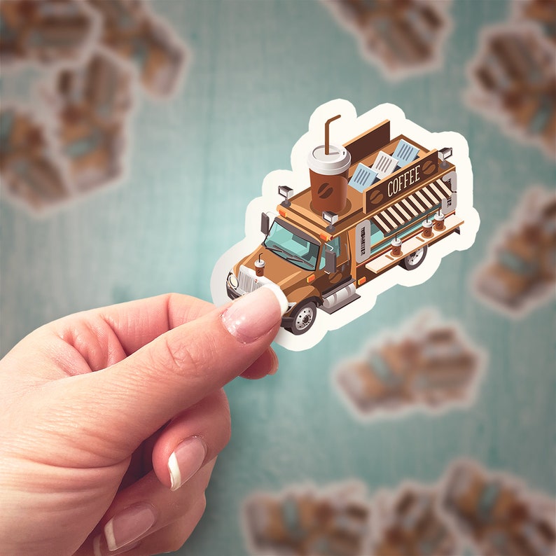 May include: A sticker of a brown coffee truck with a coffee cup on top. The truck has the word "COFFEE" on the side. The sticker is held by a hand against a teal background with other blurred stickers.