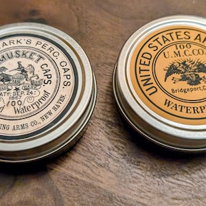 May include: Two vintage metal tins with labels. One reads "J. Goldmark's Perc. Caps. U.S. Musket Caps. Waterproof." The other reads "United States Army Caps. 100 U.M.C. Co. Waterproof."