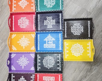 May include: A collection of eleven rectangular wooden serving trays in various colors including orange, green, pink, yellow, blue, purple, black, and red. Each tray features a unique white hand-painted geometric pattern and a white dotted border.