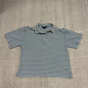 Puede incluir: Un polo de manga corta con rayas horizontales en verde azulado y blanco. La camisa tiene cuello y tapeta de tres botones. La tela parece ser un tejido de punto ligero.