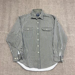 May include: A long-sleeved button-down shirt by GAP featuring a vertical striped pattern in dark green and off-white. The shirt includes a standard collar, a front button placket, two chest pockets with buttoned flaps, and buttoned cuffs at the wrists.