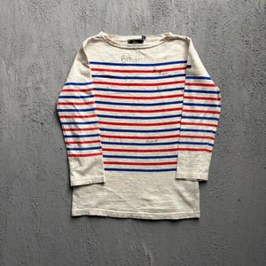 May include: A long-sleeve shirt in an off-white color featuring horizontal red and blue stripes. The shirt has a boat neckline and includes handwritten black ink text across the chest area, including the name Bill Perkins and other markings.