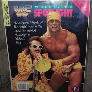 May include: A vintage WWF Wrestling Spotlight magazine cover featuring Hulk Hogan and Jimmy Hart. The cover has the text "Wrestling Spotlight" in pink and white. Jimmy Hart is holding a megaphone, and Hogan is pointing. The magazine is in a protective sleeve.