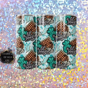 May include: Three stainless steel tumblers with a turquoise and brown patterned design. The pattern features a chequered design, lightning bolts, and the text "a lil' bouzie".
