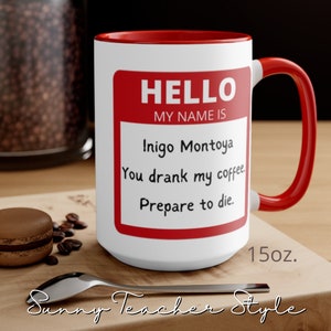 May include: White ceramic mug with a red rim and handle. The mug has a red name tag that says "HELLO MY NAME IS Inigo Montoya You drank my coffee. Prepare to die." The mug is 15 ounces.