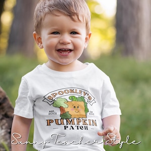 May include: A white toddler t-shirt with a cute pumpkin graphic and the text "Spookley's est. 2001 Pumpkin Patch be kind".